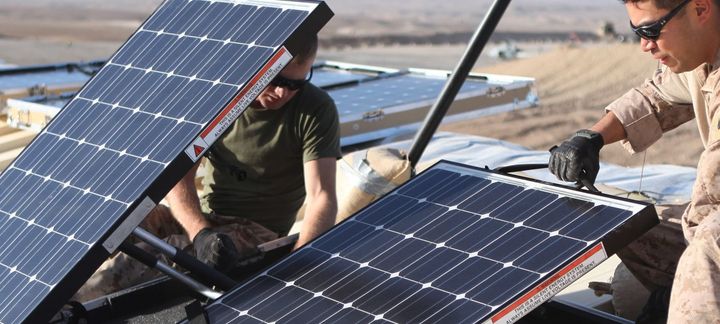 Two men are working on solar panels in the desert