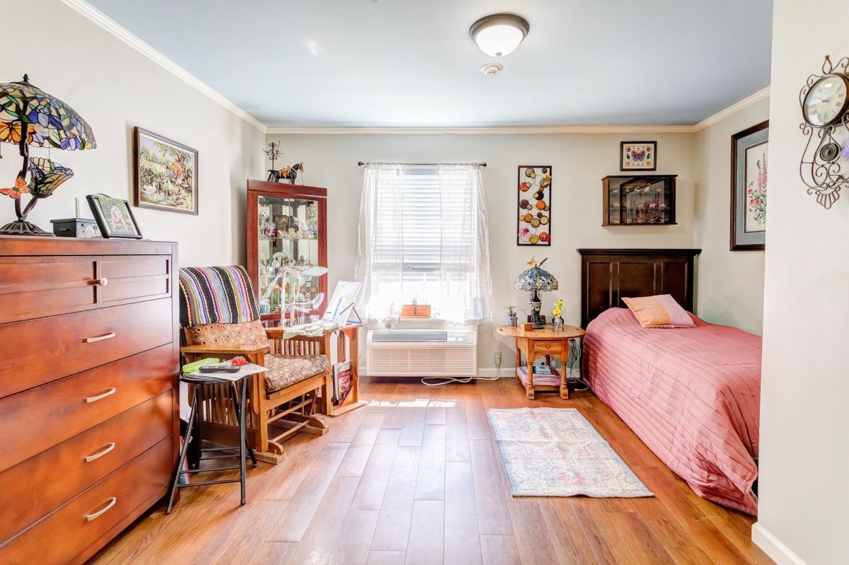 A bedroom with two beds , a dresser , a chair and a window.