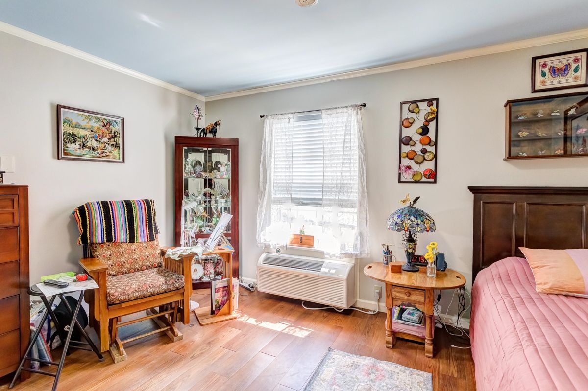 A bedroom with a bed , chair , nightstand and dresser.