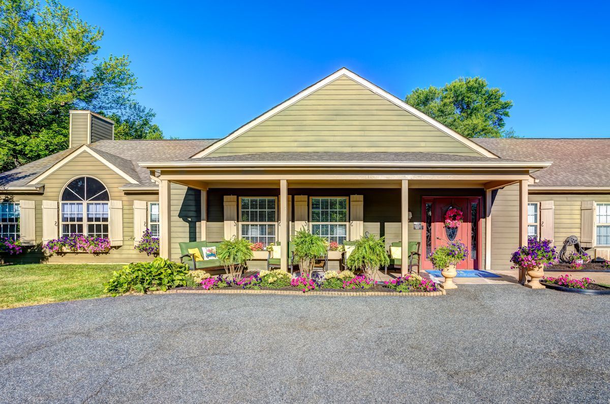 A large house with a large porch and a gravel driveway.