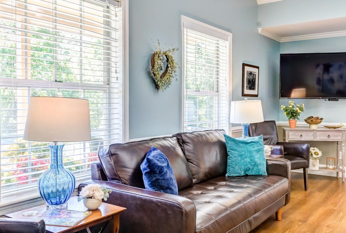 A living room with a couch , chairs , lamps , and a flat screen tv.