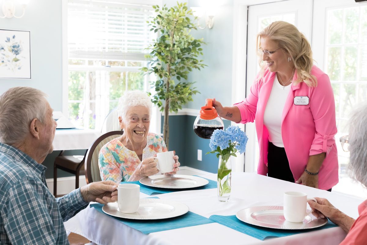A woman is pouring coffee to a group of elderly people sitting at a table.