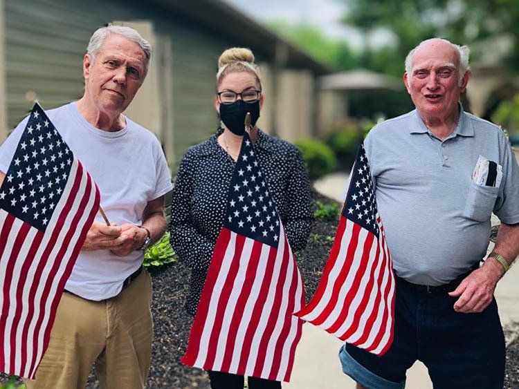 Three people are standing next to each other holding american flags.