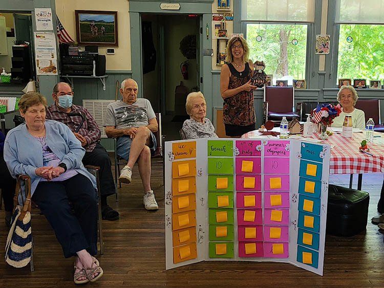 A group of elderly people are sitting around a table in a room.