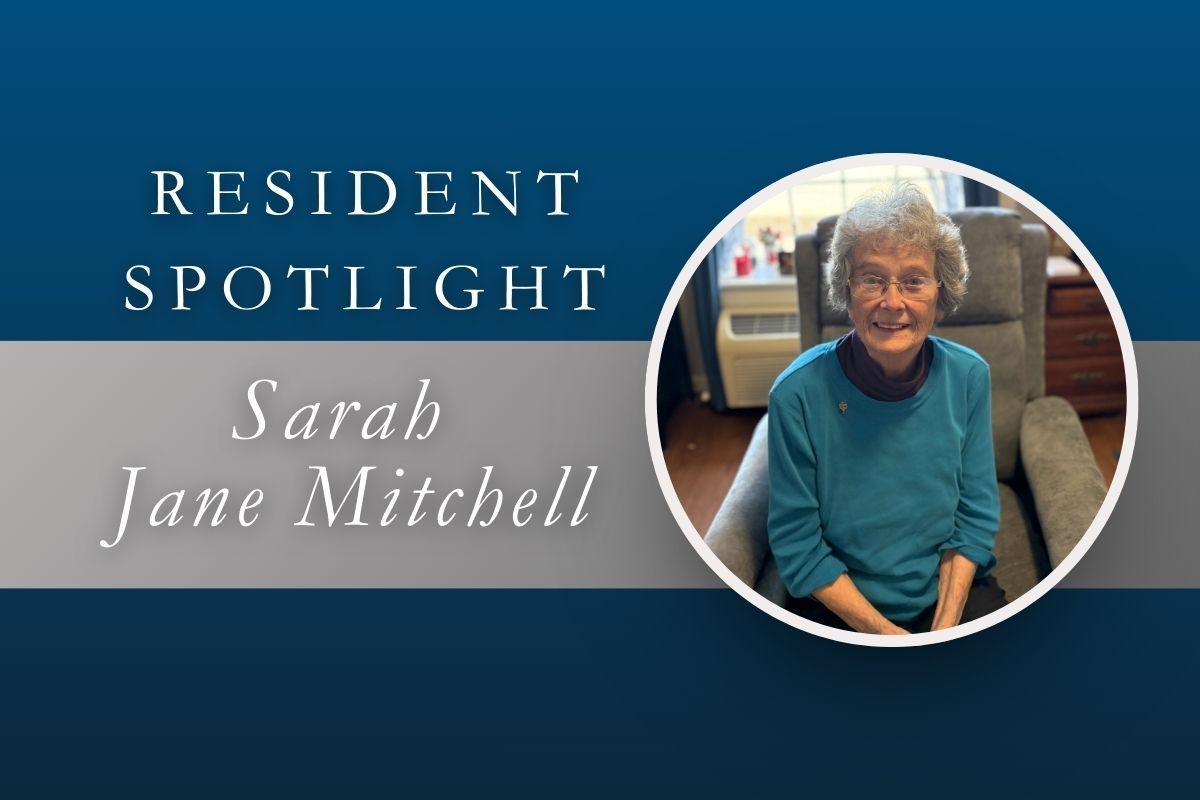 Resident spotlight for Sarah Jane Mitchell. A woman seated in a chair, smiling, inside a building.