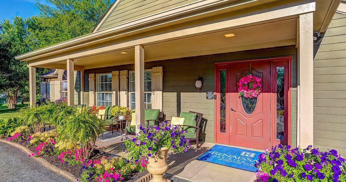 A house with a porch and flowers in front of it.