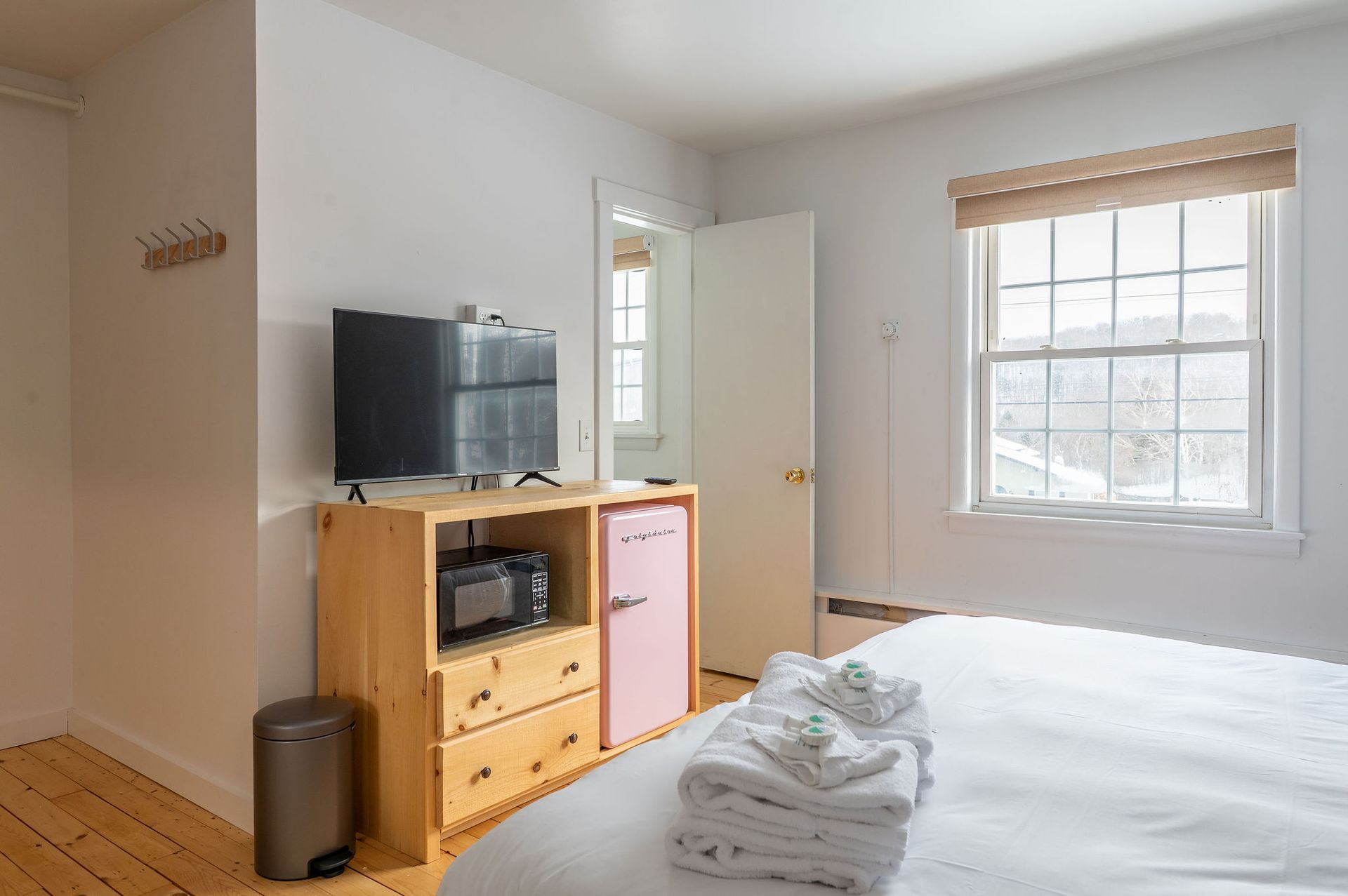 Bedroom with a bed, TV, dresser, mini-fridge, and window.