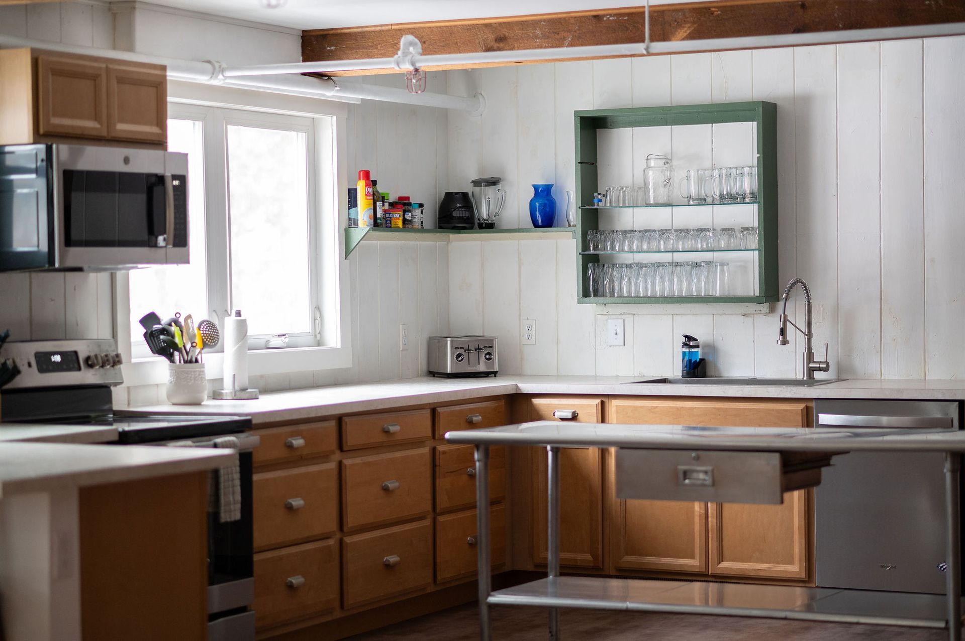 Kitchen interior with light wood cabinets, stainless steel appliances, and a window.