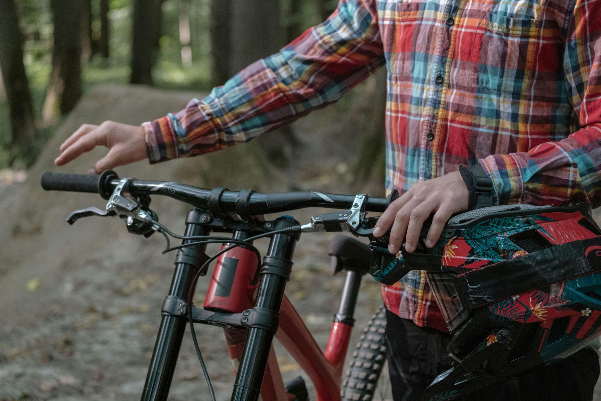 Cyclist on mountain bike rides through a sandy forest path, wearing helmet and sunglasses.