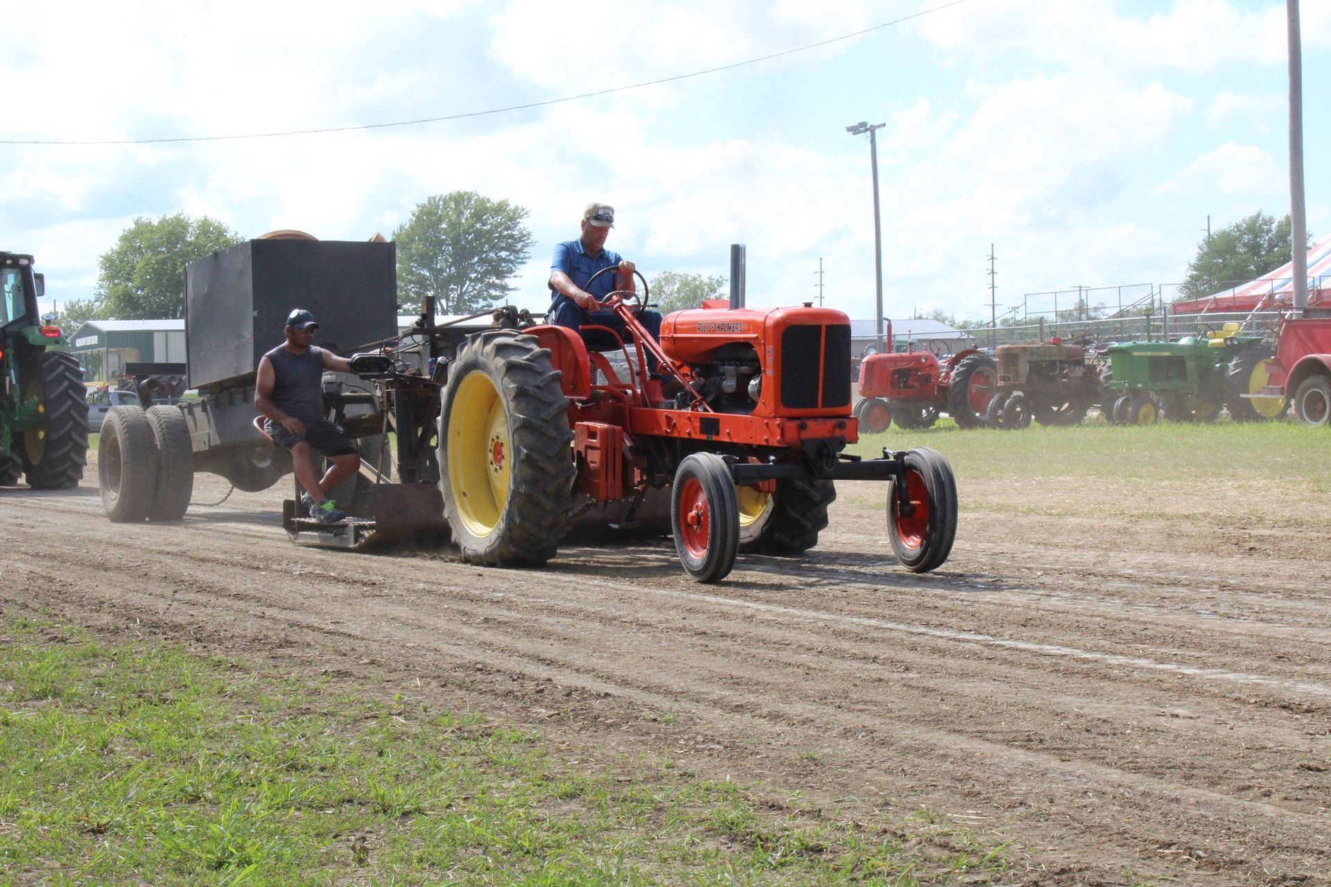 Old orange Allis Chalmers tractor pulling equipment