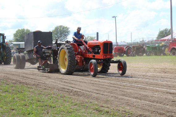 Old orange Allis Chalmers tractor pulling equipment