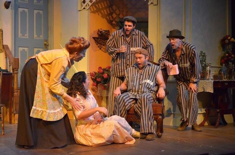 Play scene: Woman comforts another, several men in pajamas react. Interior setting with ornate details.