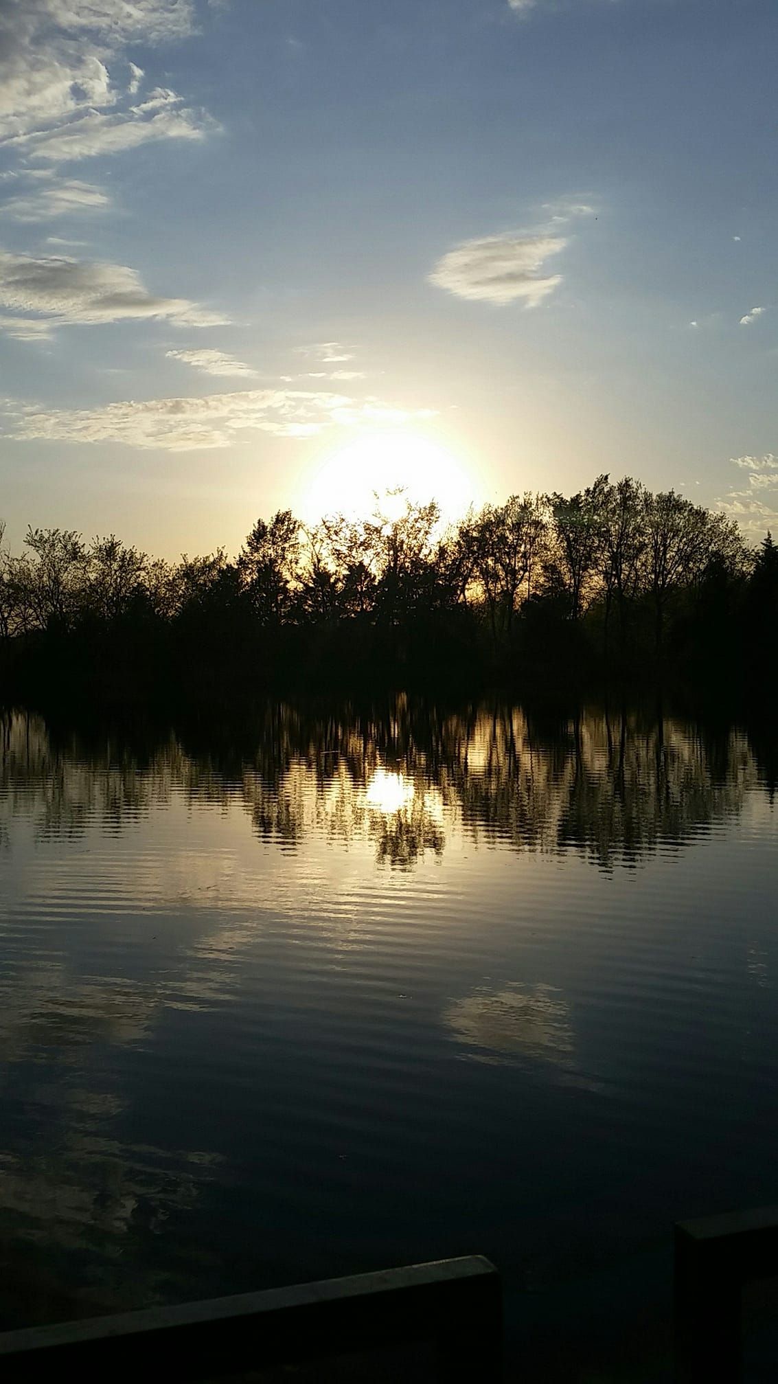Sunset over calm water reflecting trees and the sky.