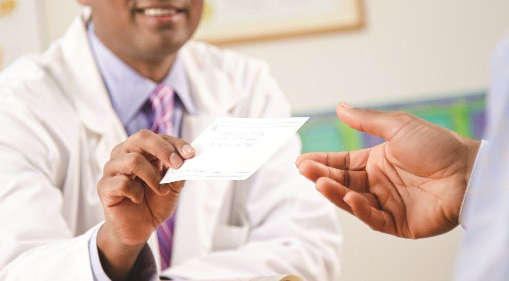 Doctor handing a prescription to a patient.