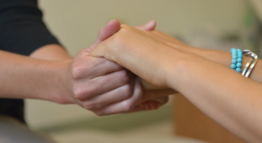 A person is holding another person 's hand in a close up of their hands.