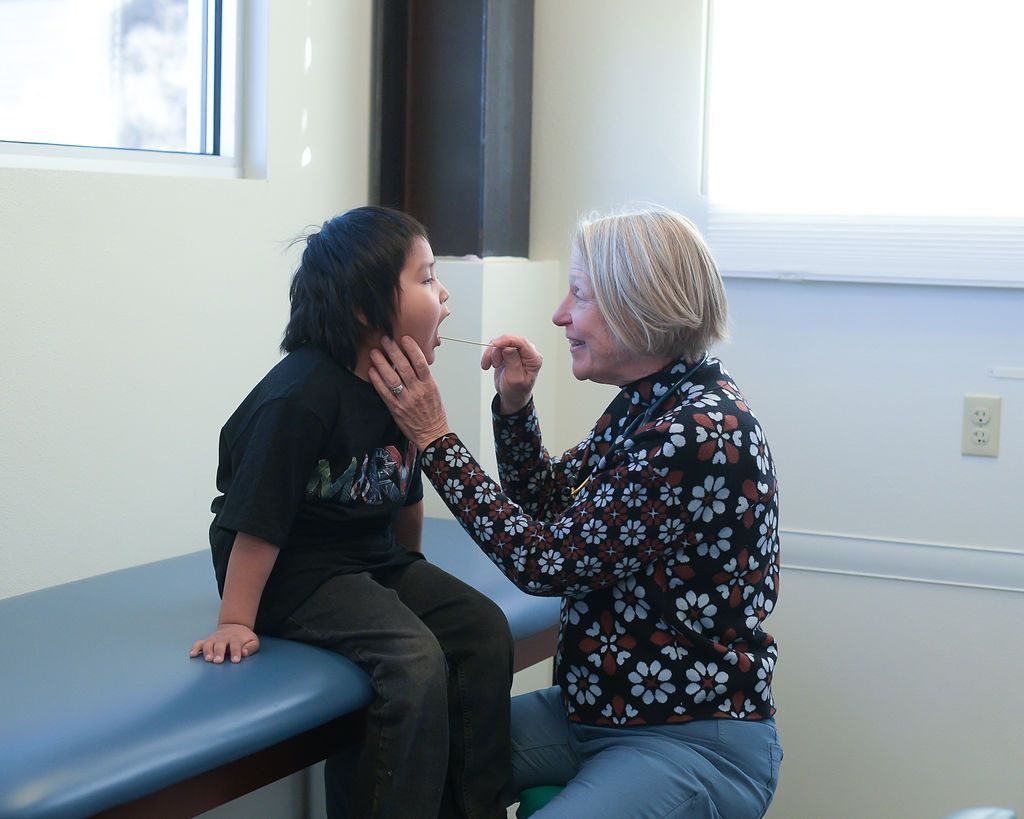 A pediatrician is examining a toddler