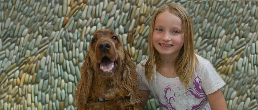 A little girl is posing for a picture with a dog.