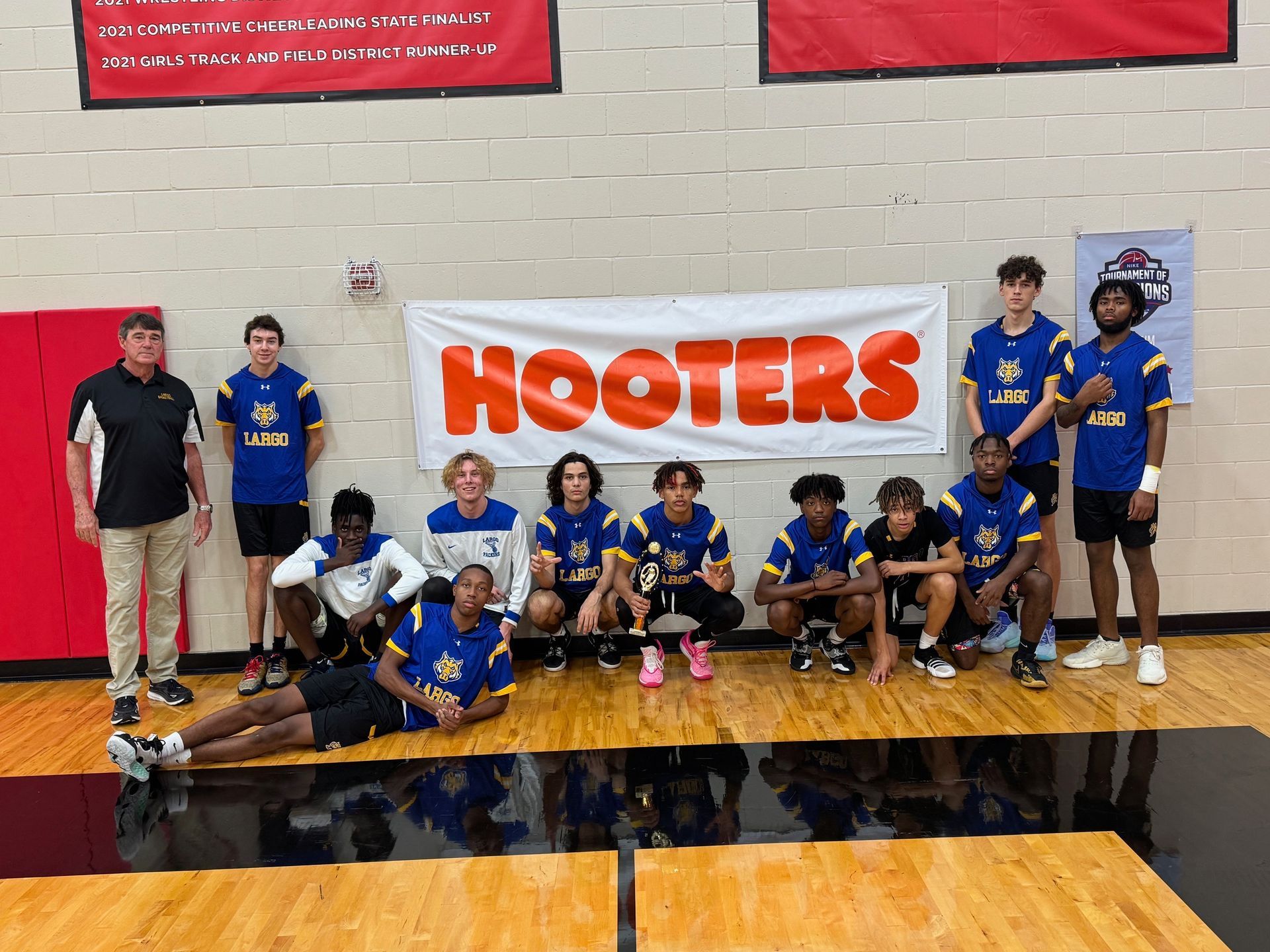 Basketball player in white jersey dunks the ball over an opponent in a dark arena.