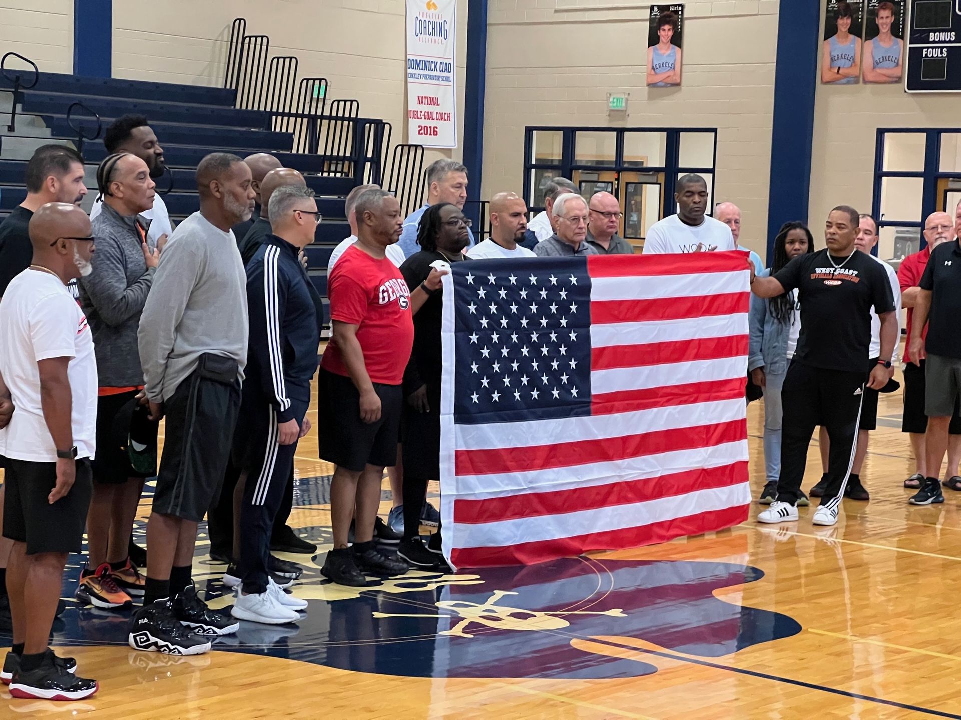 Basketball player in red uniform dunks the ball; crowded arena, other players jump, fans watch.