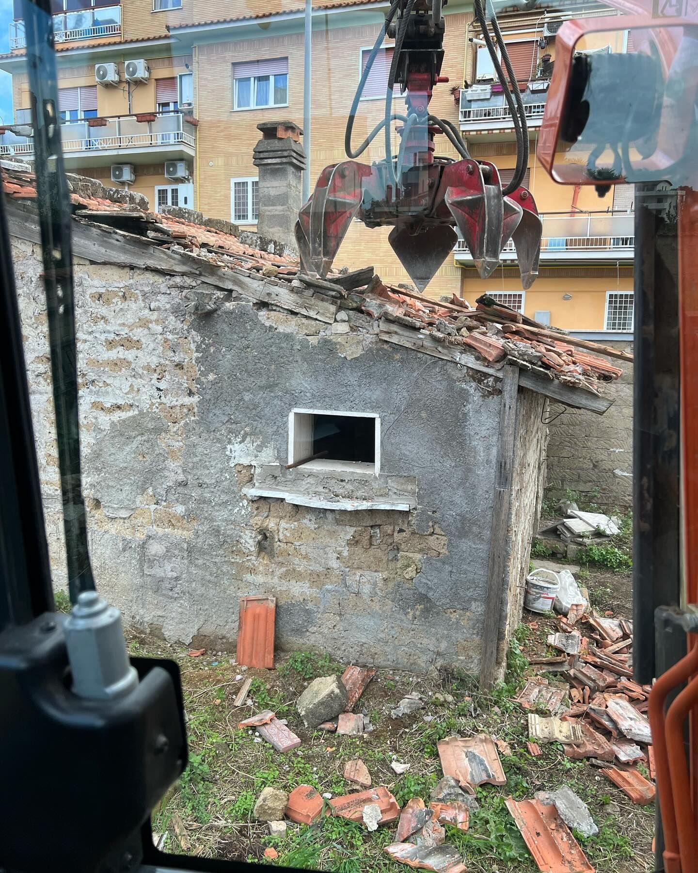 Un edificio in mattoni viene demolito da una gru.