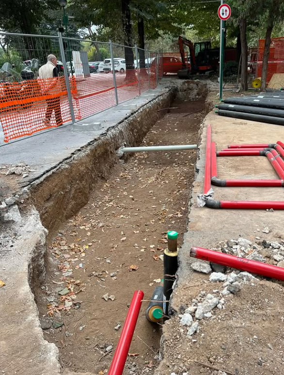 Un buco nel terreno con dei tubi rossi dentro