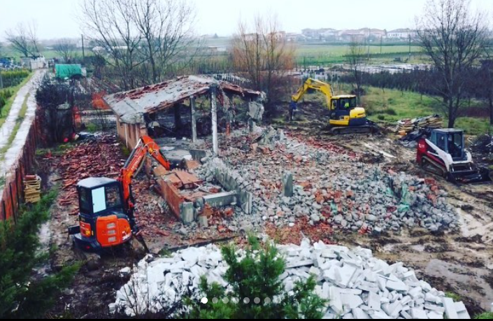 Un grande mucchio di rocce e mattoni viene demolito da un escavatore.