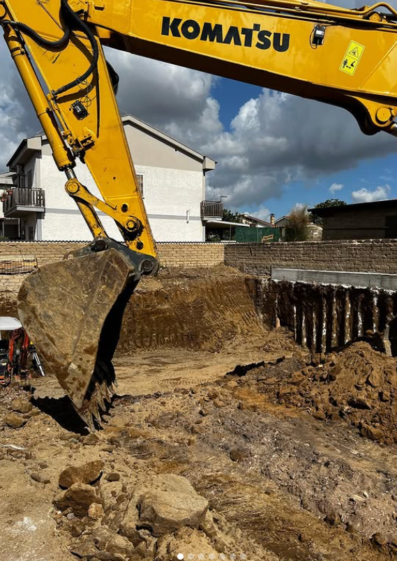 Un escavatore giallo Komatsu sta scavando una buca