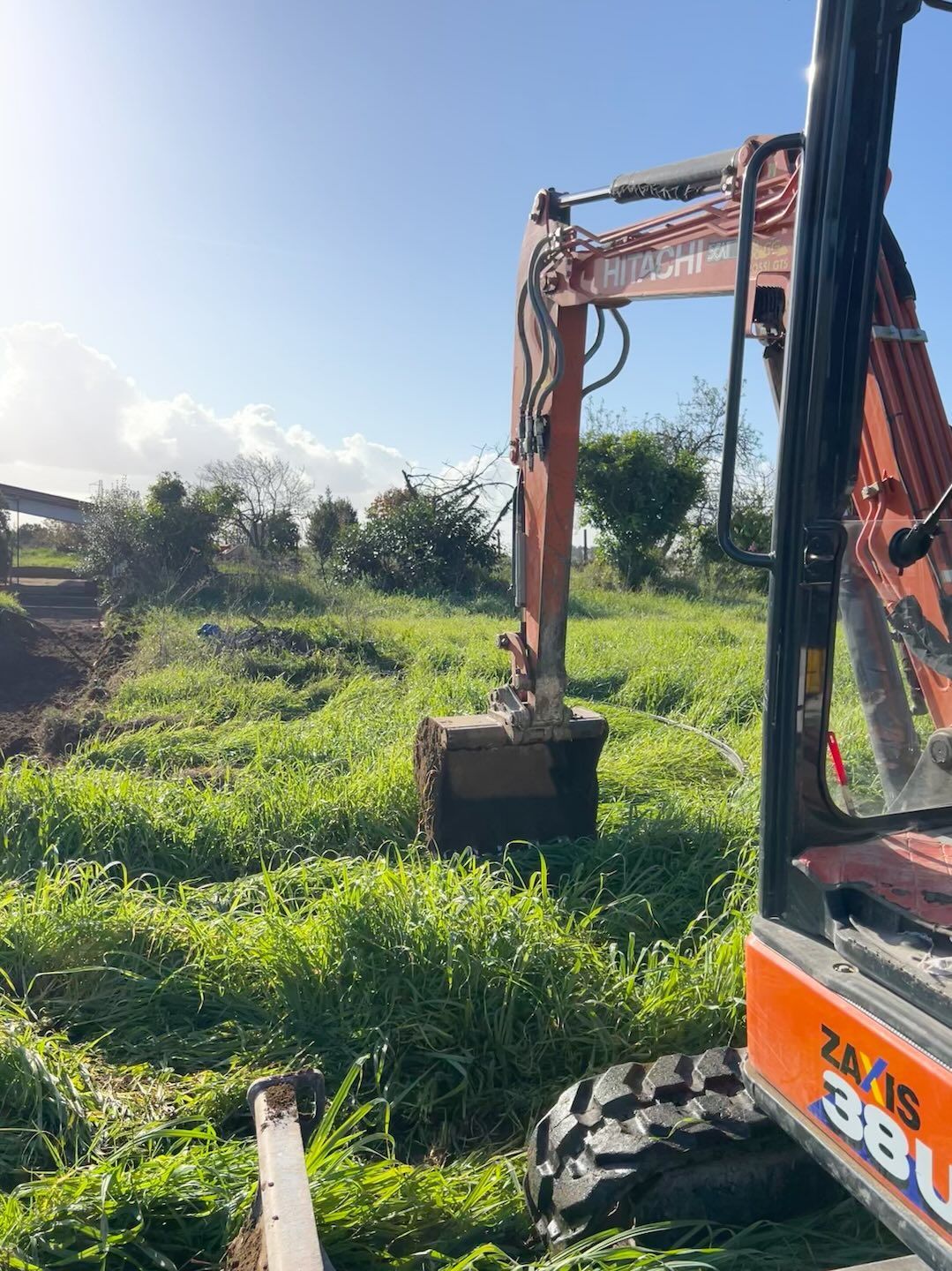 Un escavatore sta scavando una buca in un campo erboso.