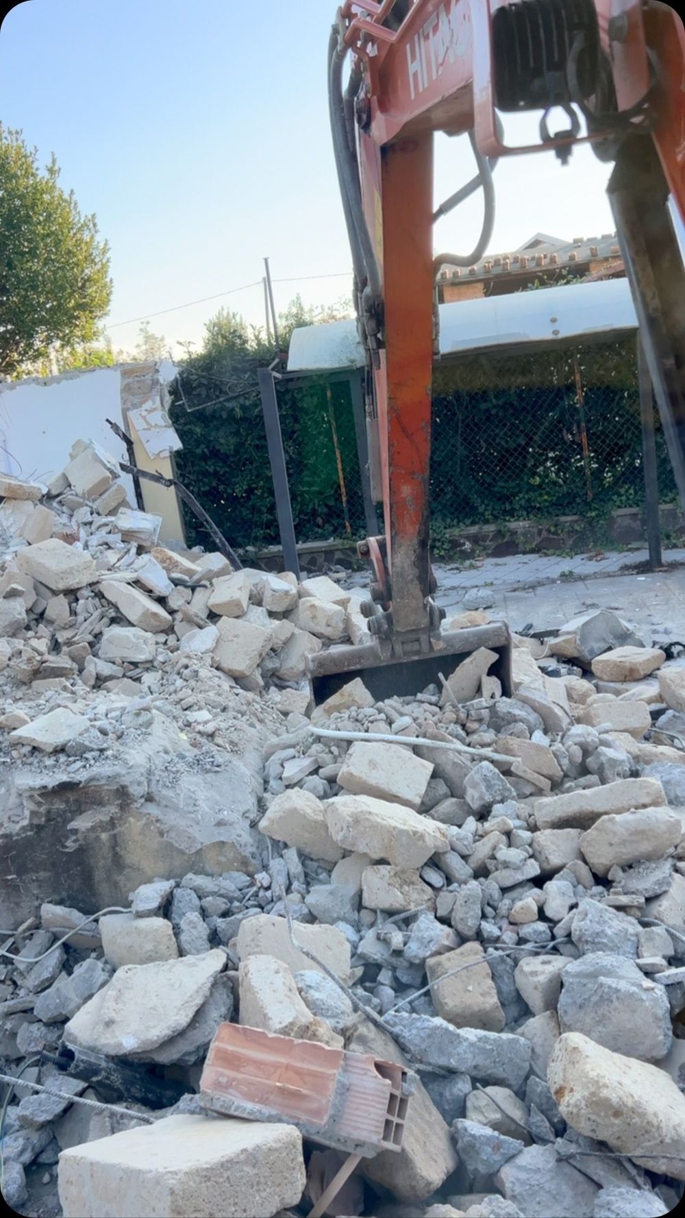 Un grande mucchio di rocce e mattoni viene demolito da un escavatore.