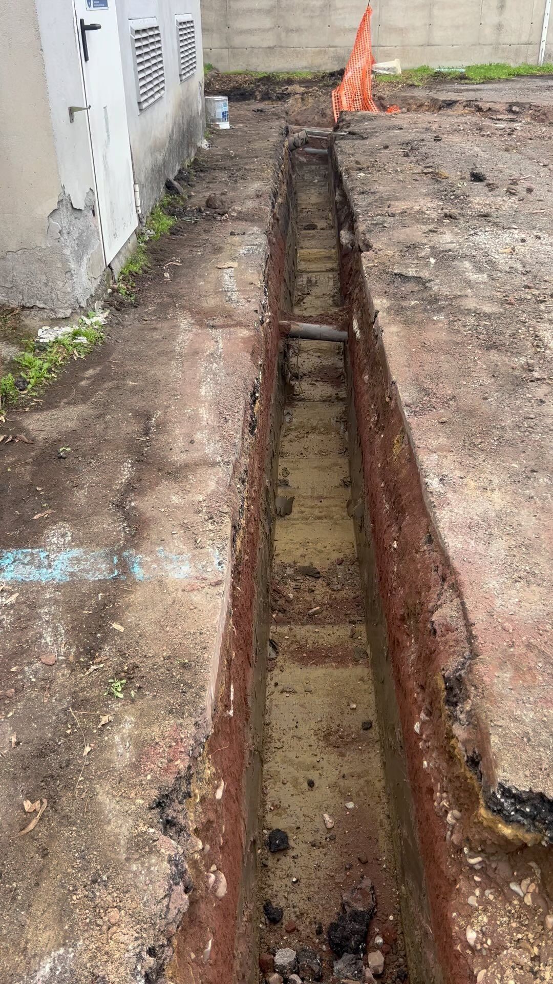 Si sta scavando una trincea nel terreno accanto a un edificio.