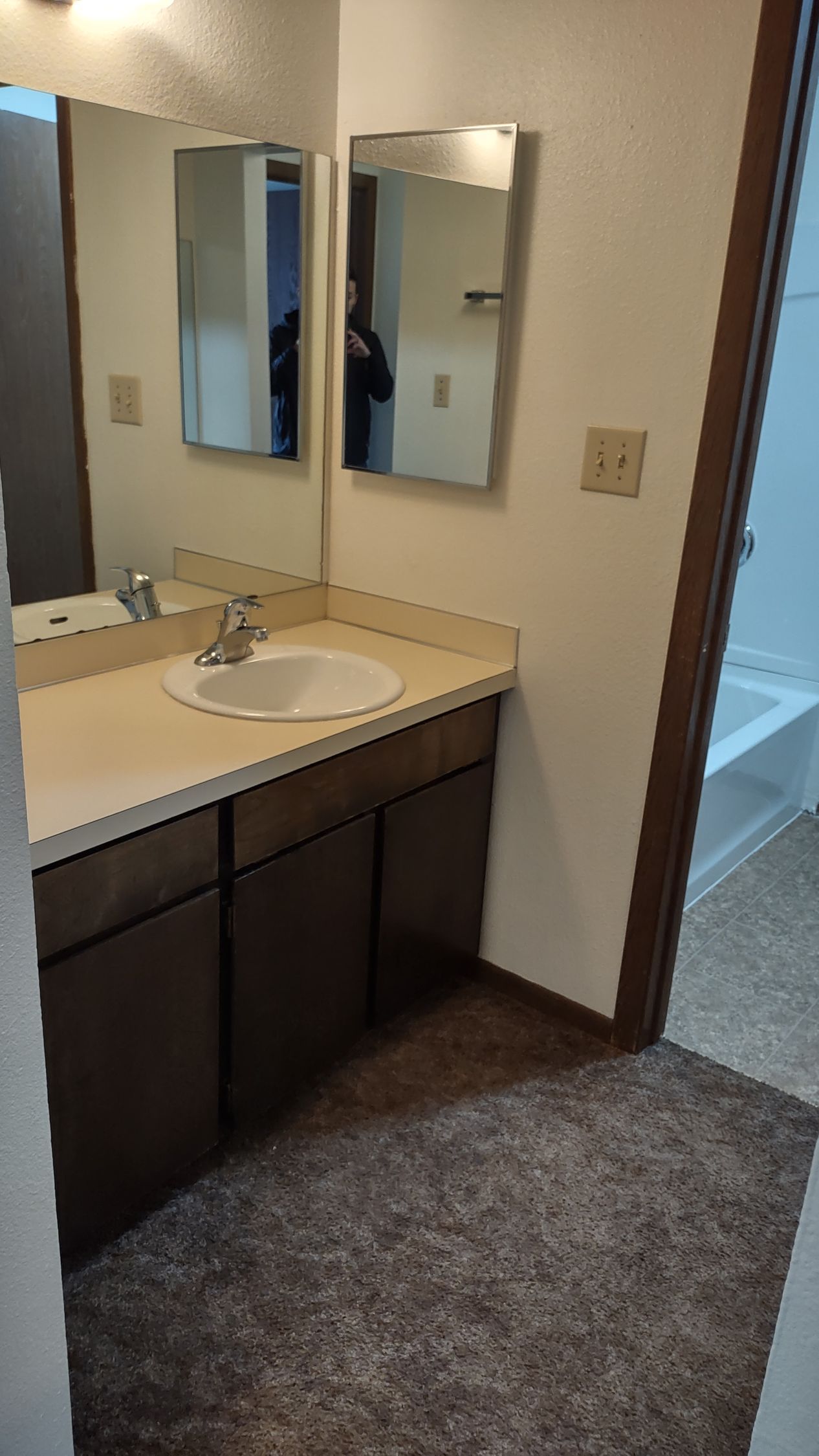 A bathroom with a sink , mirrors and a bathtub.