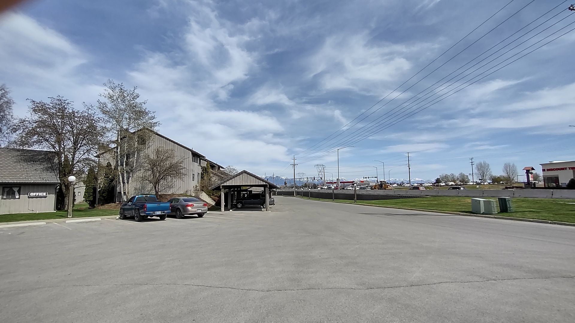 A parking lot with cars parked in front of a building on a sunny day.