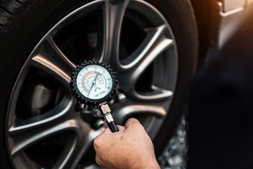 Hand using a tire pressure gauge on a car wheel close-up