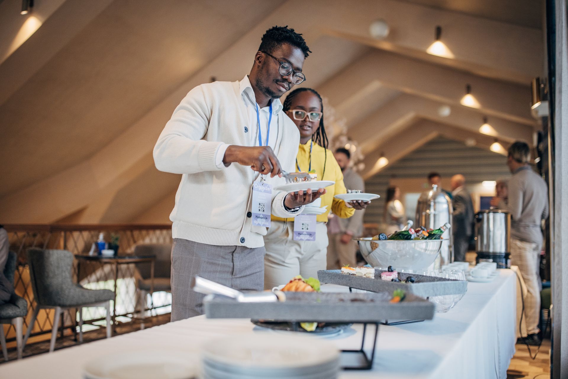 A man and a woman are standing at a buffet table.