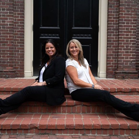 Two women are sitting on the steps of a building.