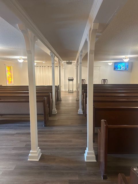 Interior of a funeral home with rows of pews, a central aisle, and a podium at the front.