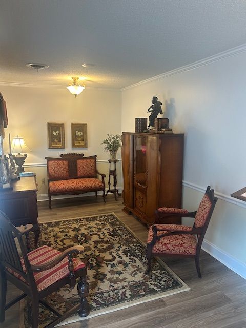 Living room with antique furniture, rug, and artwork.