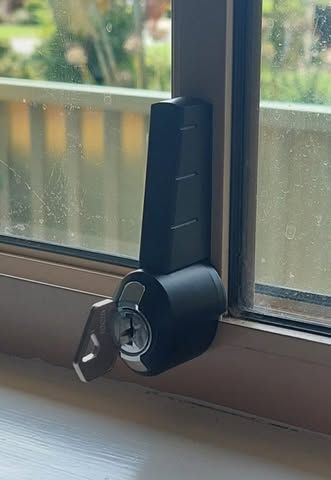 A Black, Vertical Window Sash Lock With a Key Inserted — Above and Beyond Locksmiths in Pimpama, QLD
