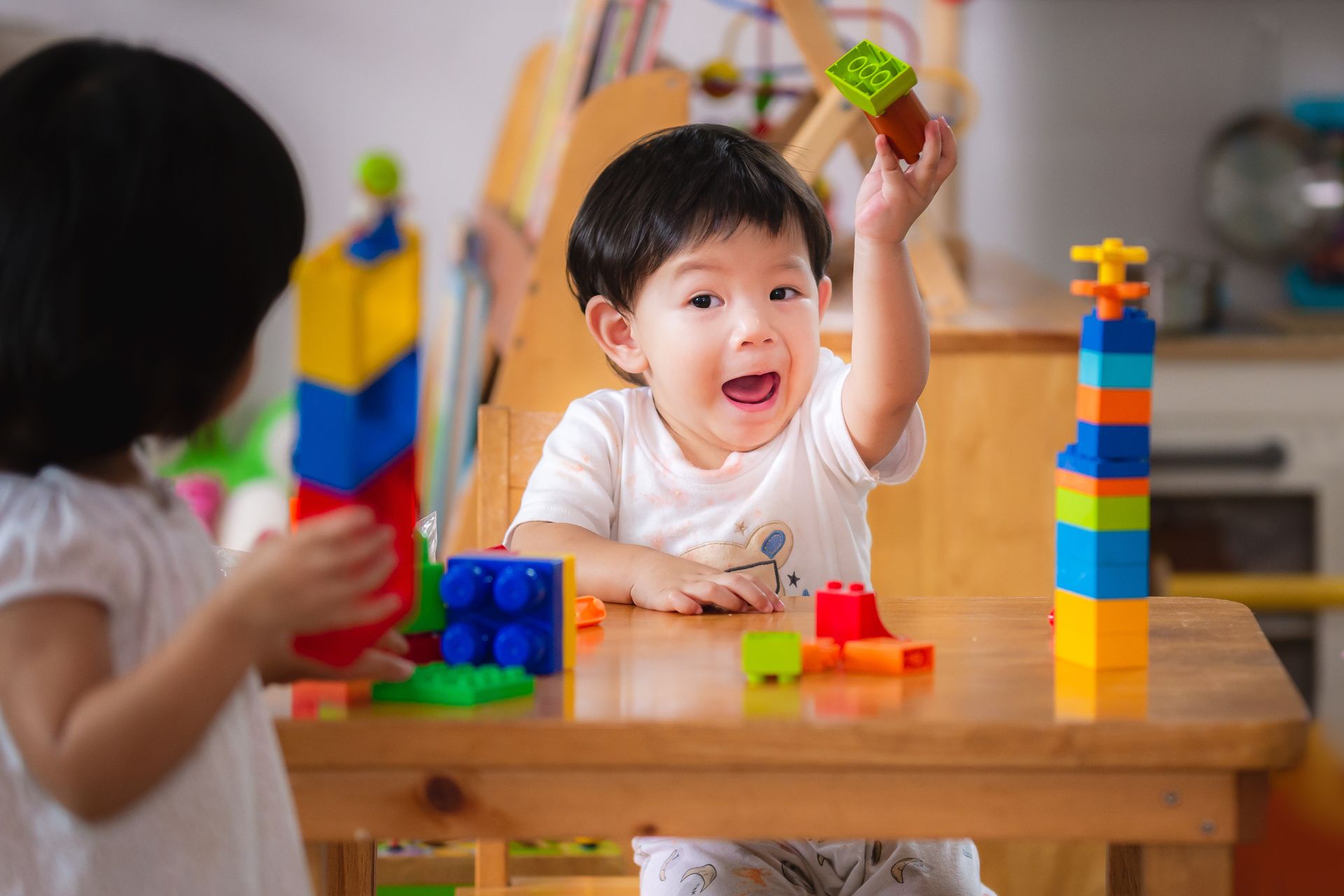 A boy and a girl are playing with lego blocks at a table.