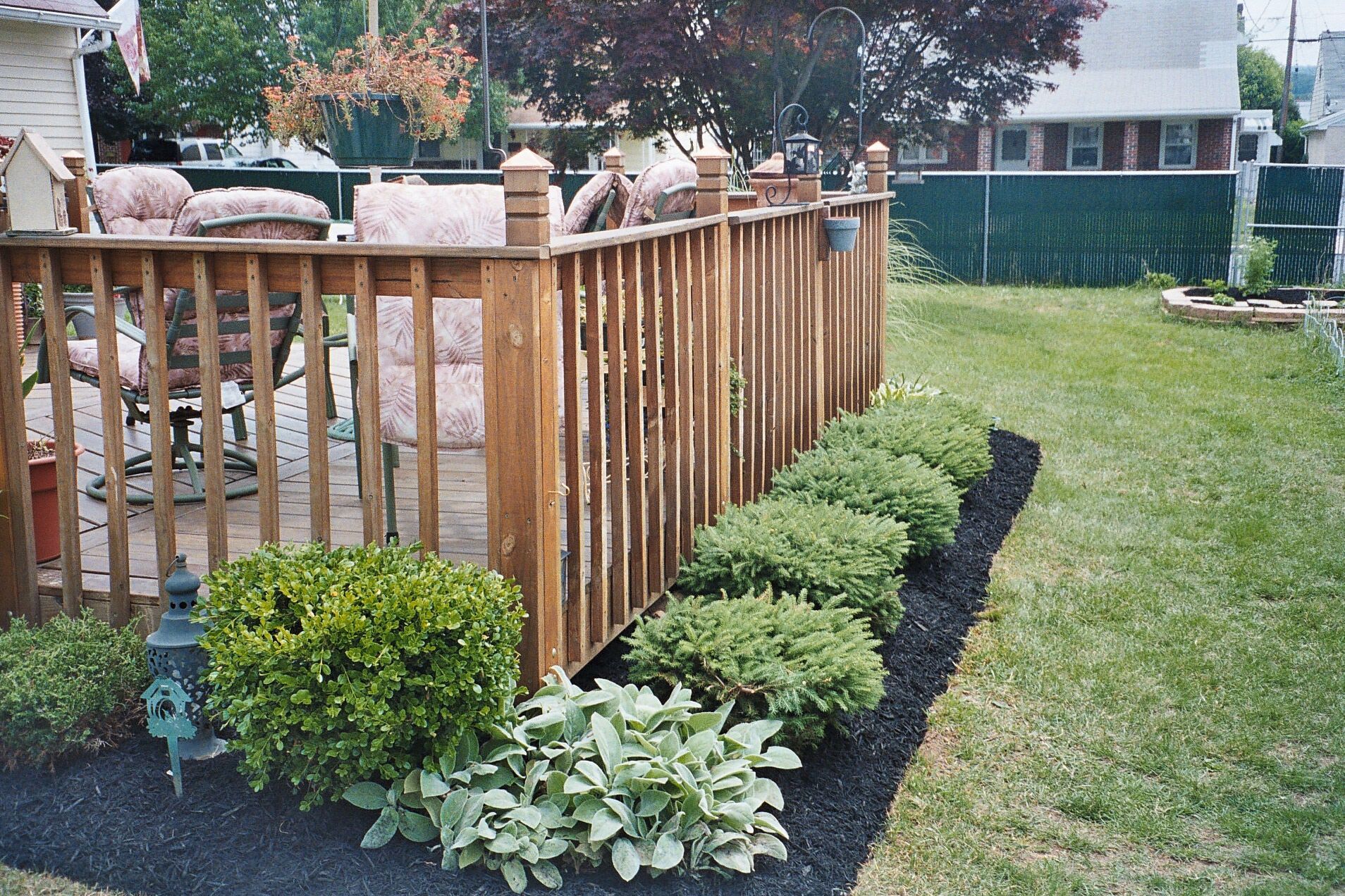 A wooden fence surrounds a deck in a backyard
