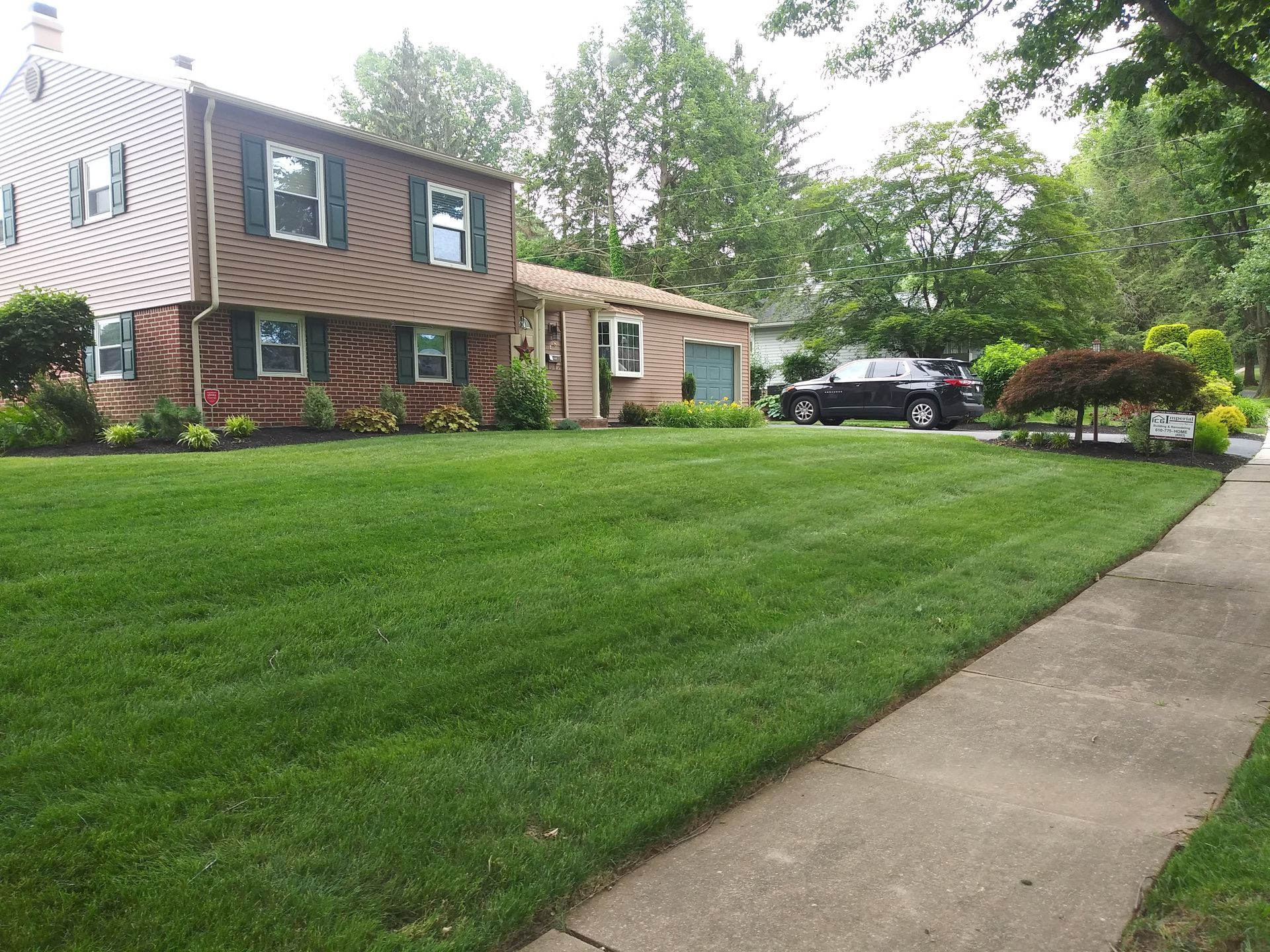 A house with a lush green lawn and a car parked in front of it