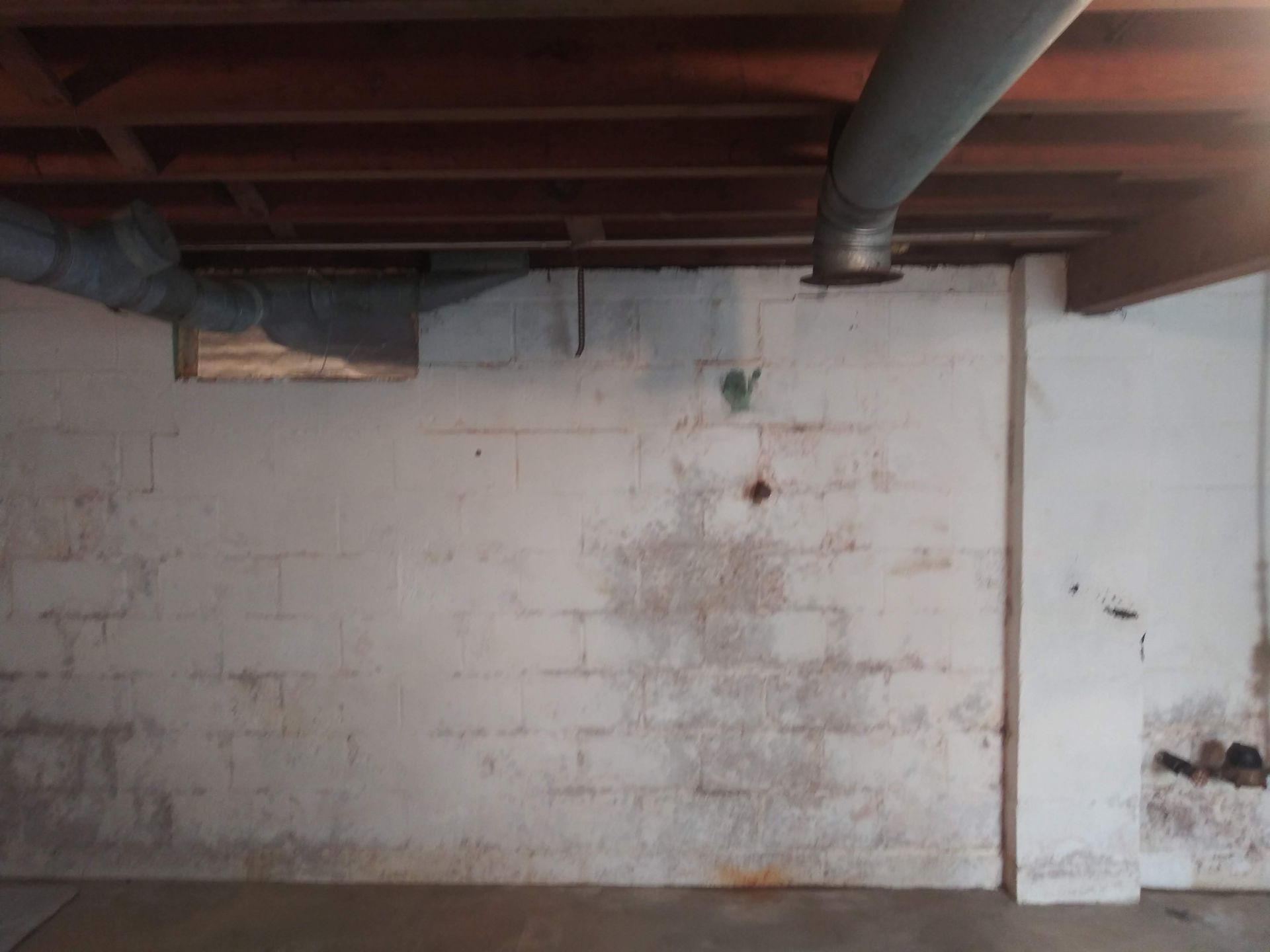 An empty basement with a brick wall and a wooden ceiling.