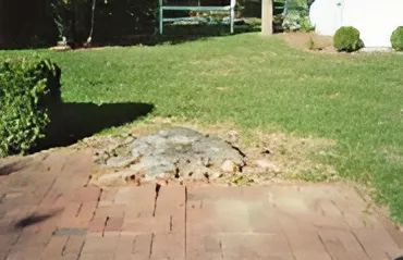 A brick walkway leading to a lush green lawn.