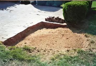 A pile of dirt is sitting in the grass next to a bush