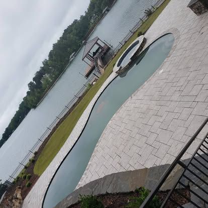 A large swimming pool with a hot tub next to a lake.