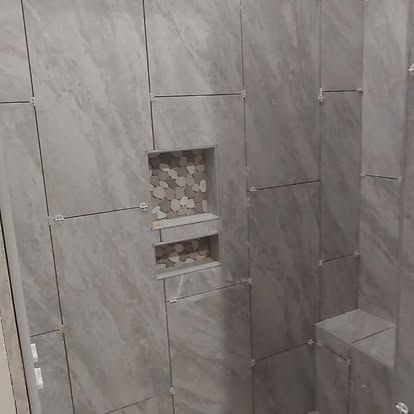 A bathroom with gray tiles and a niche in the wall.