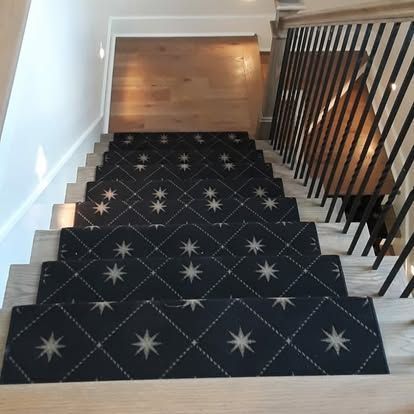 A staircase with a black carpet and white stars on it.