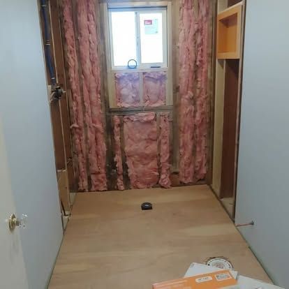 A room with pink insulation on the walls and a window.