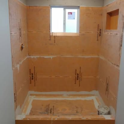 A bathroom under construction with a window and a bucket on the floor.