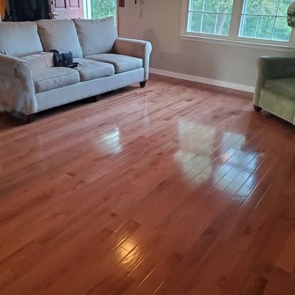 A living room with hardwood floors , a couch and a chair.